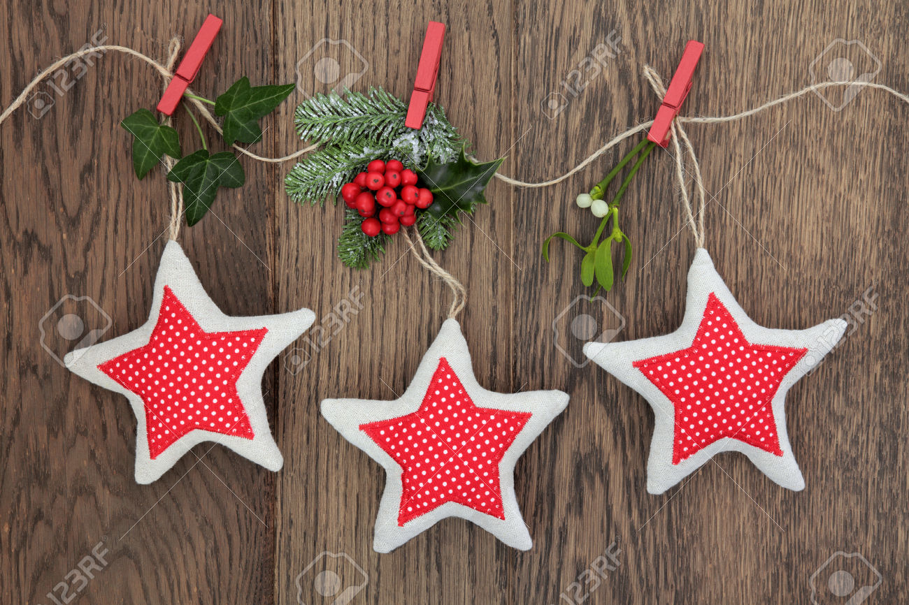 Christmas star decorations with holly, ivy, fir and mistletoe hanging on a string line over oak background.