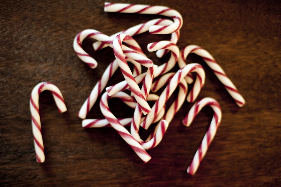 Christmas candy treats with a pile of traditional red and white striped candy canes on a dark background, viewed from above
